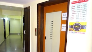 Pasillo de hotel con una puerta de madera y un letrero que indica acceso a ascensores.