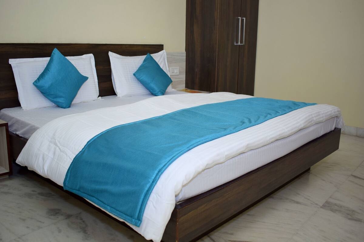 Un letto con una testiera in legno, biancheria bianca e tocchi di blu.