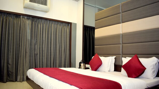 Una habitación de hotel con una cama grande, cabecera de madera y ventana con cortinas.