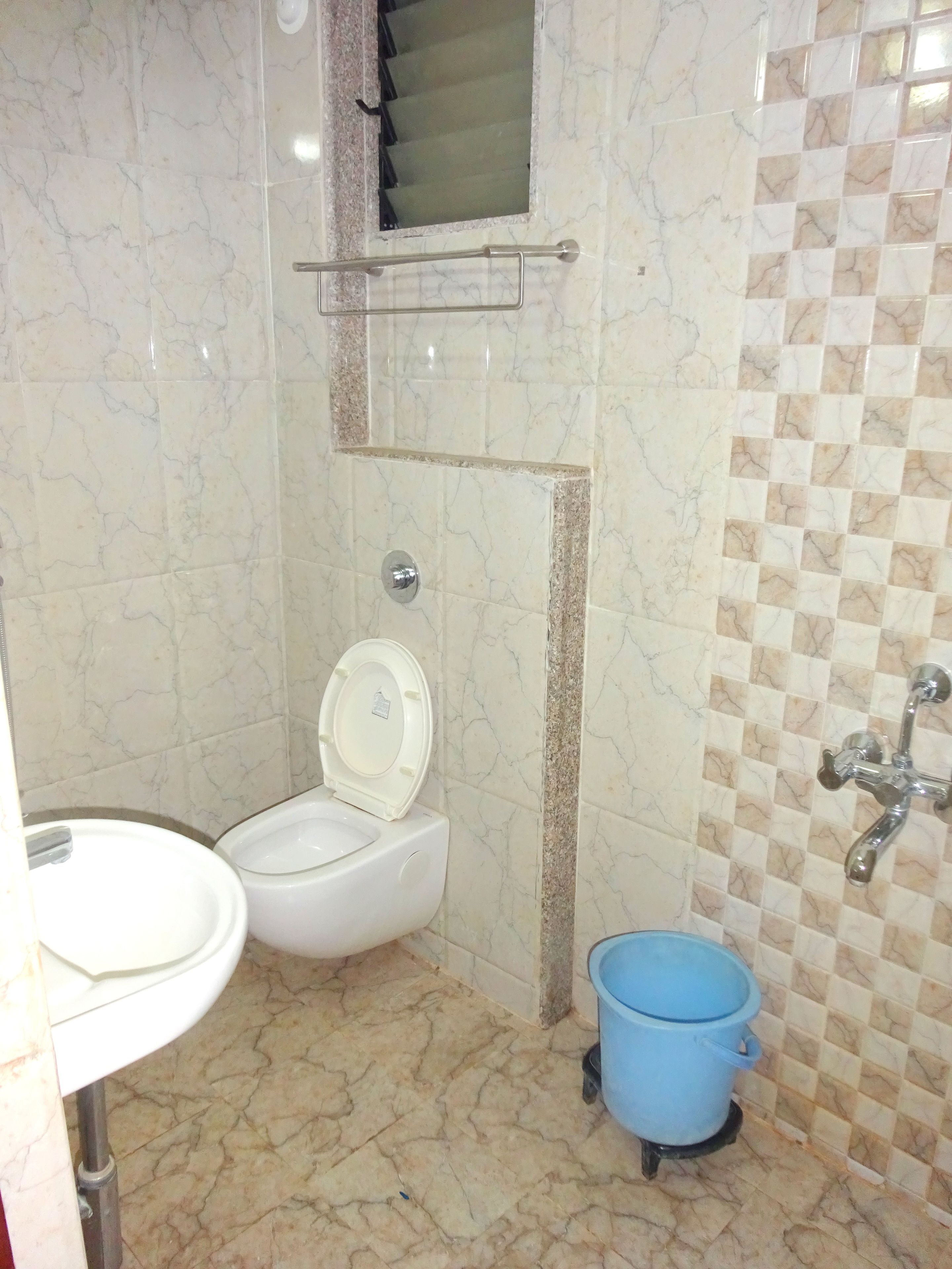 Un baño con inodoro, lavabo y un cubo azul.