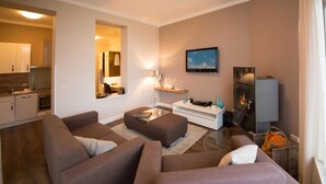 A modern living room with a sofa set, a coffee table, a fireplace, and a television.