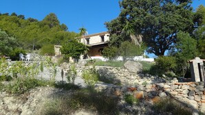 Un mur de pierres, avec un bâtiment en pierre au style rustique en arrière-plan.