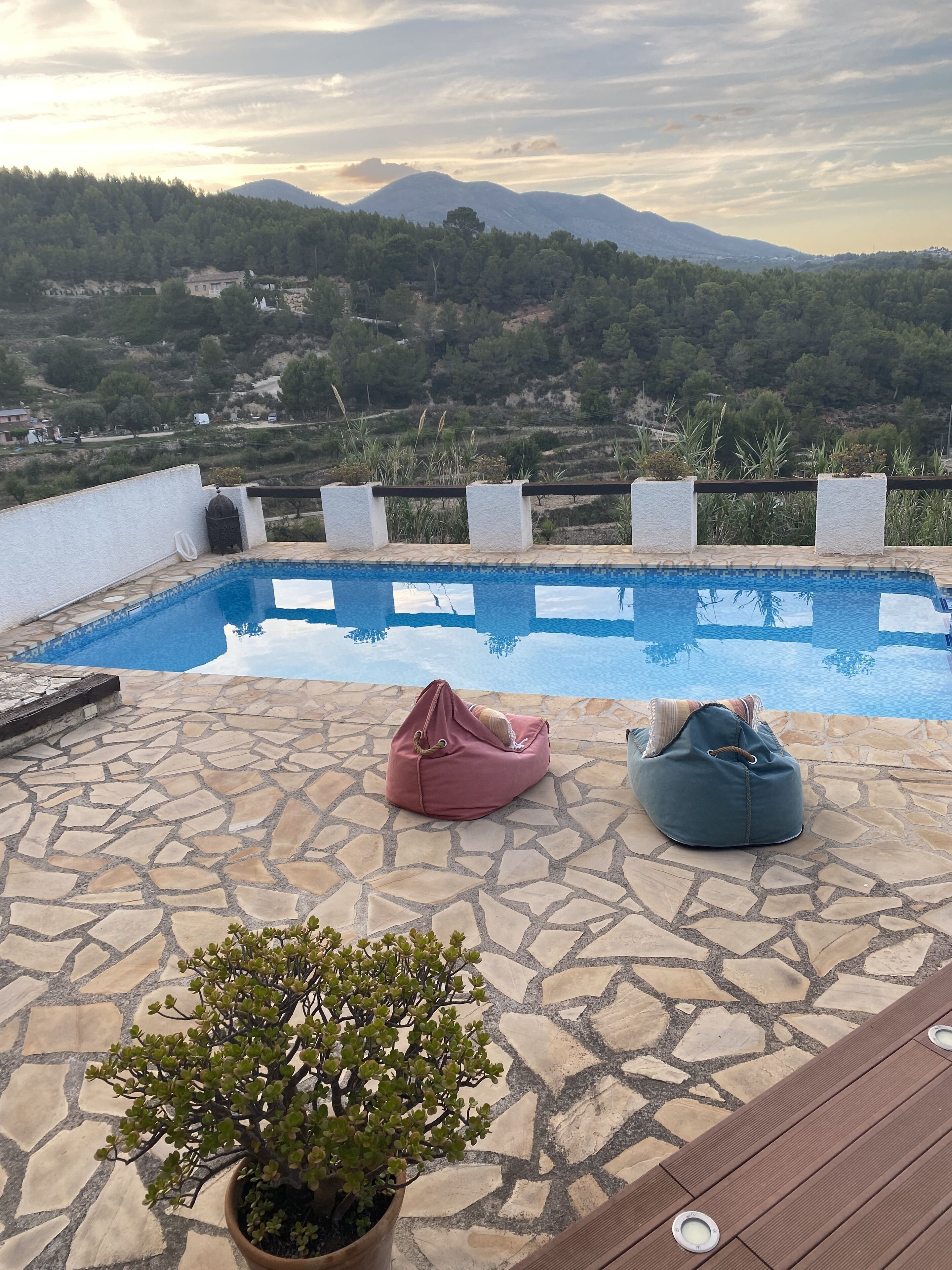 Un espace piscine doté d’un sol en pierre, de deux fauteuils en forme de sac et d’une plante en pot.