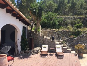 A patio with lounge chairs, a stone wall, and a staircase leading up a hill. - Country house, "Las Ruinas" with pool between almond trees and olive groves. (Benissa)