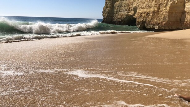 A beach with waves crashing onto the shore, a sandy beach, and a large cliff. - Modern, quietly located vacation apartment with sea view + close to the beach, fully air-conditioned (Carvoeiro (Vale Centeanes))