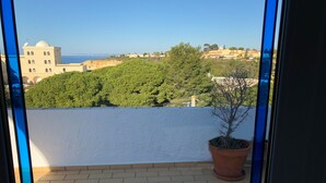 A balcony with a view of a coastal town, a potted plant, and a clear sky. - Modern, quietly located vacation apartment with sea view + close to the beach, fully air-conditioned (Carvoeiro (Vale Centeanes))