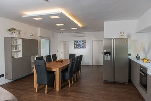 Una cocina moderna con una mesa de comedor, sillas, un refrigerador y un horno empotrado.
