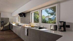 A modern kitchen with a large island, stainless steel appliances, and a view of greenery outside. - CASA ENGELSBURG. Calpe (Calpe/Alicante)