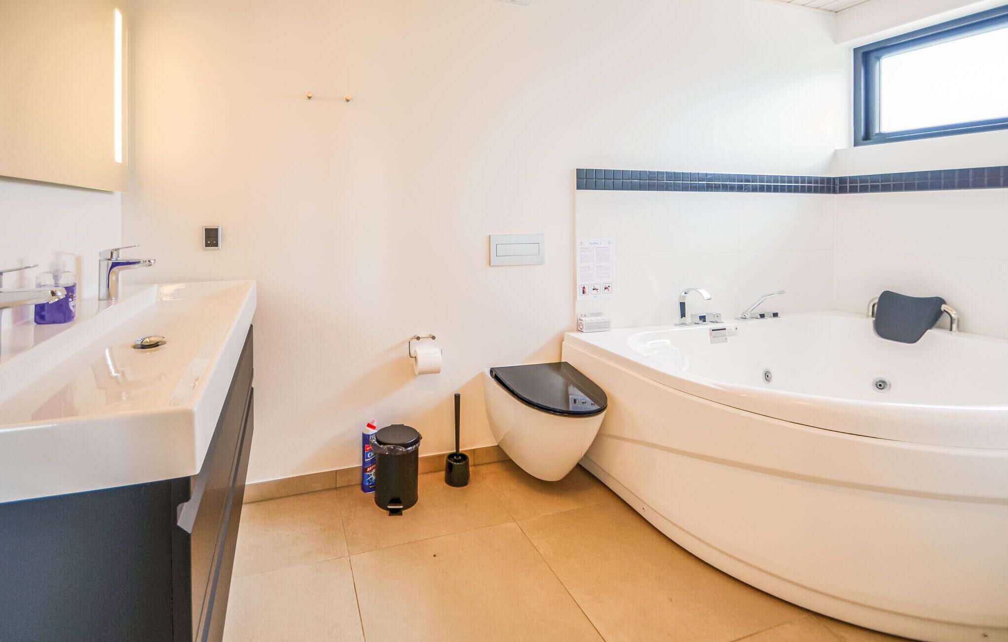 Een moderne badkamer met een ruime badkuip, een apart toilet en een wastafel met spiegel.