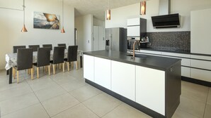 Une cuisine moderne dotée d’un îlot central, de luminaires suspendus, d’un coin repas avec des chaises et d’un îlot de cuisine avec un évier.