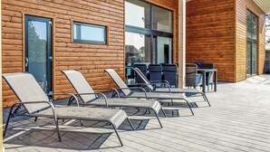 Un bâtiment en bois doté d’un espace extérieur aménagé, abrité et comprenant des fauteuils et des tables.