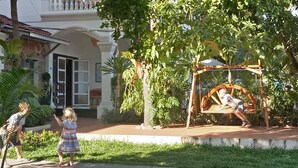 A child playing on a swing set in a garden area with a house in the background. - Aster Villa (Siem Reap)