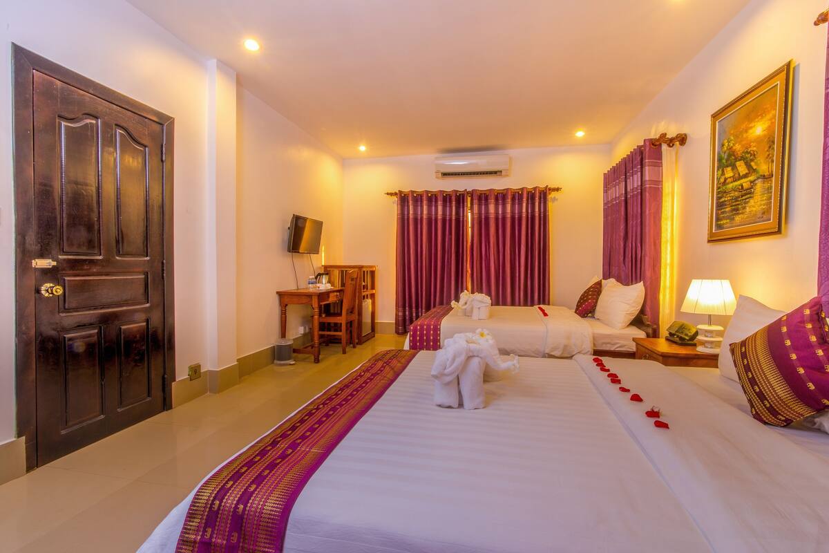 A hotel room with a large bed, a desk, a chair, and a television.
