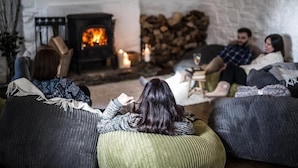 A cozy living room with a fireplace, comfortable seating, and a rustic stone wall. - The elbowroom escape (Donard)