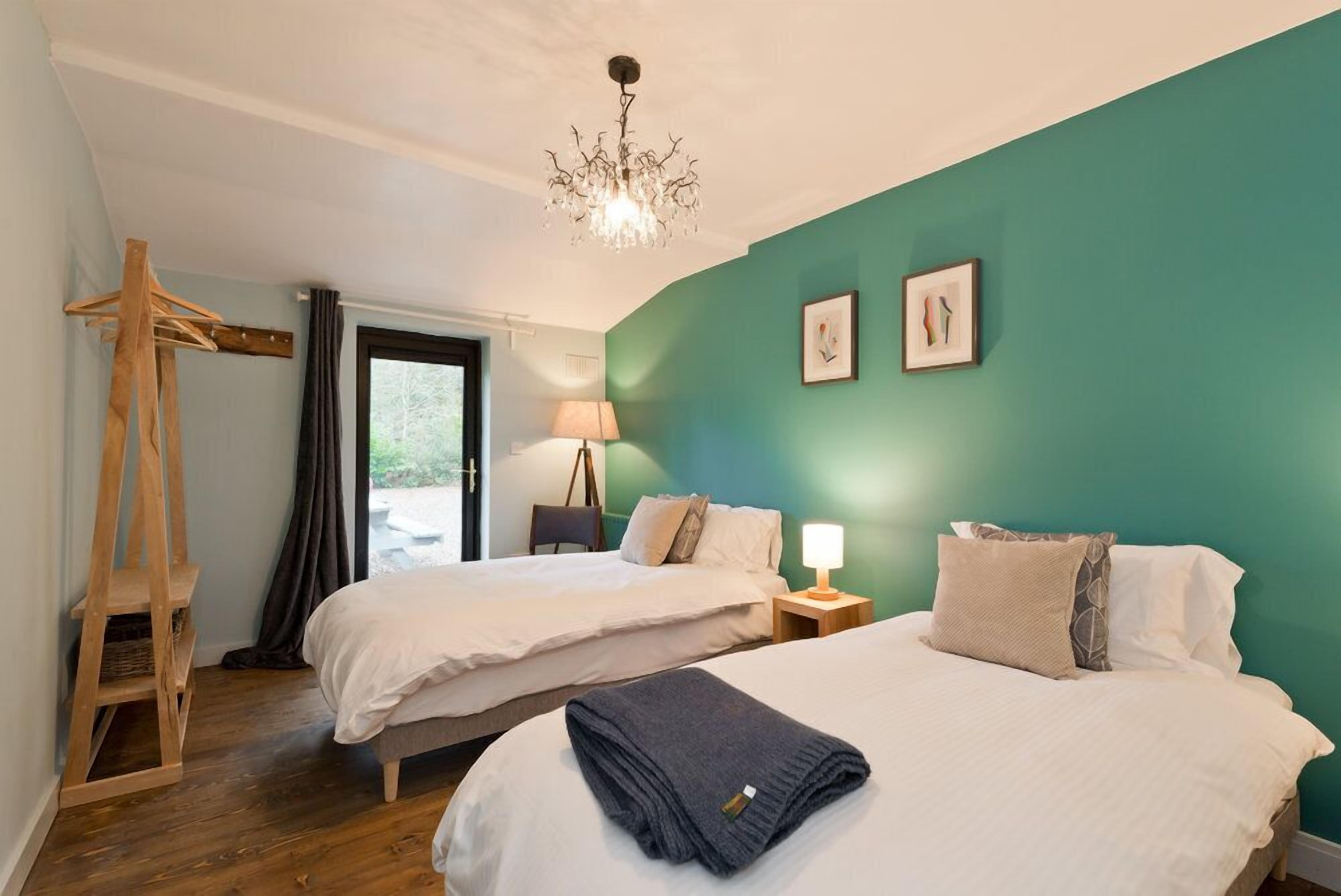 A bedroom with two beds, a wooden ladder, a lamp, and a chandelier.