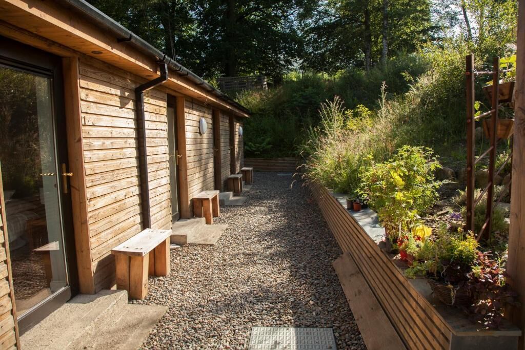 A wooden building with benches and a gravel path.