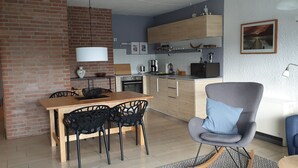 Una cocina moderna con armarios de madera, una mesa de comedor con sillas, un sillón azul y un sofá.