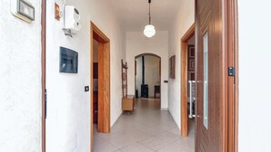 Um corredor com piso de azulejos, portas de madeira, luminária pendente e um armário de madeira.
