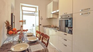 Cozinha com mesa de jantar posta para quatro, fogão e armários.