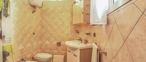 A compact bathroom with a toilet, two sinks, a mirror, and a towel rack.