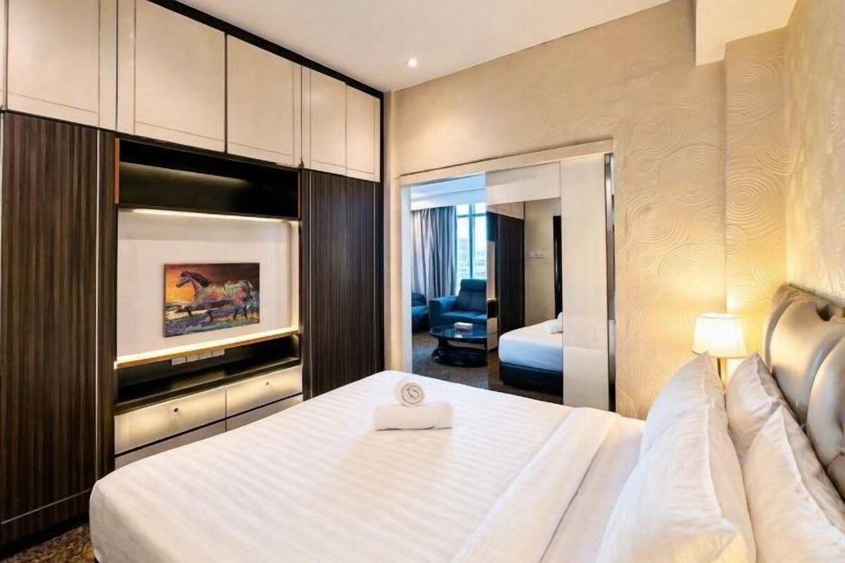 A hotel room with a bed, a desk with a computer, a TV, and a painting on the wall.
