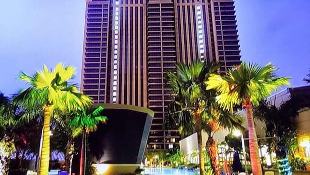A modern hotel with a large pool, palm trees, and a well-lit facade. - Times Square Service Suites (Kuala Lumpur)