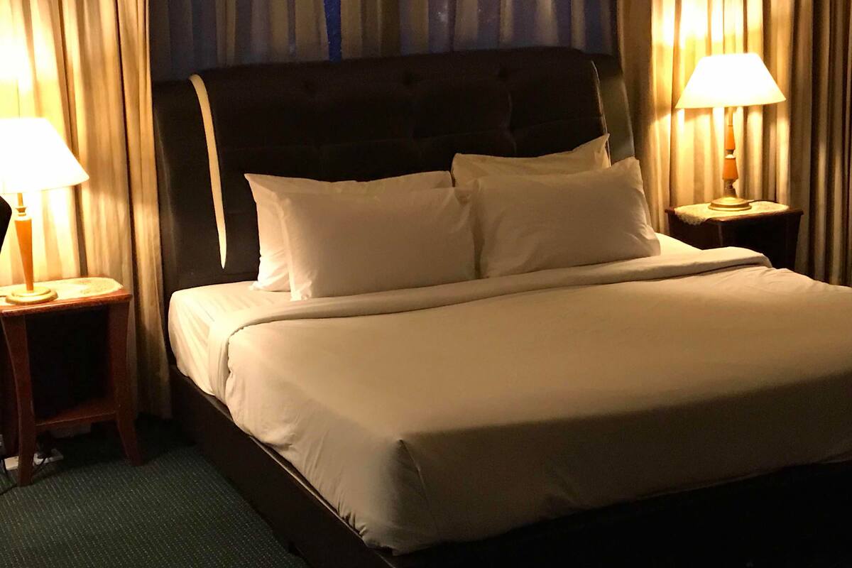 A hotel room with a large bed, two bedside tables with lamps, and curtains.