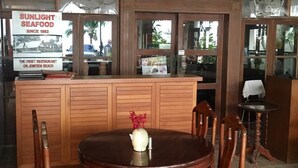 A restaurant with a wooden counter and a round table with chairs. - Sunlight Hotel (Pattaya)