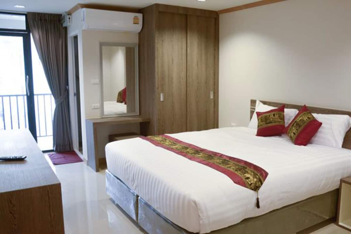 Une chambre d’hôtel avec un grand lit, une table de chevet, un miroir et une armoire.