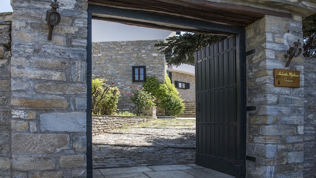 A stone building with a metal gate and a sign that reads "Andreas Moutzoura". - Arxontiko Mytilineou Skretaion (South Pelion)