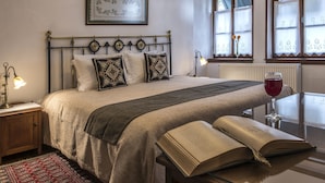 A neatly arranged bedroom with a bed, bedside table, and a reading area with a book and a glass of red wine. - Arxontiko Mytilineou Skretaion (South Pelion)