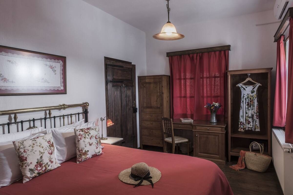 A bedroom with a bed, a desk, a chair, a wardrobe, and a hanging wardrobe.