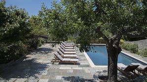 A poolside area with lounge chairs aligned in rows, a swimming pool, and a stone pathway. - Arxontiko Mytilineou Skretaion (South Pelion)