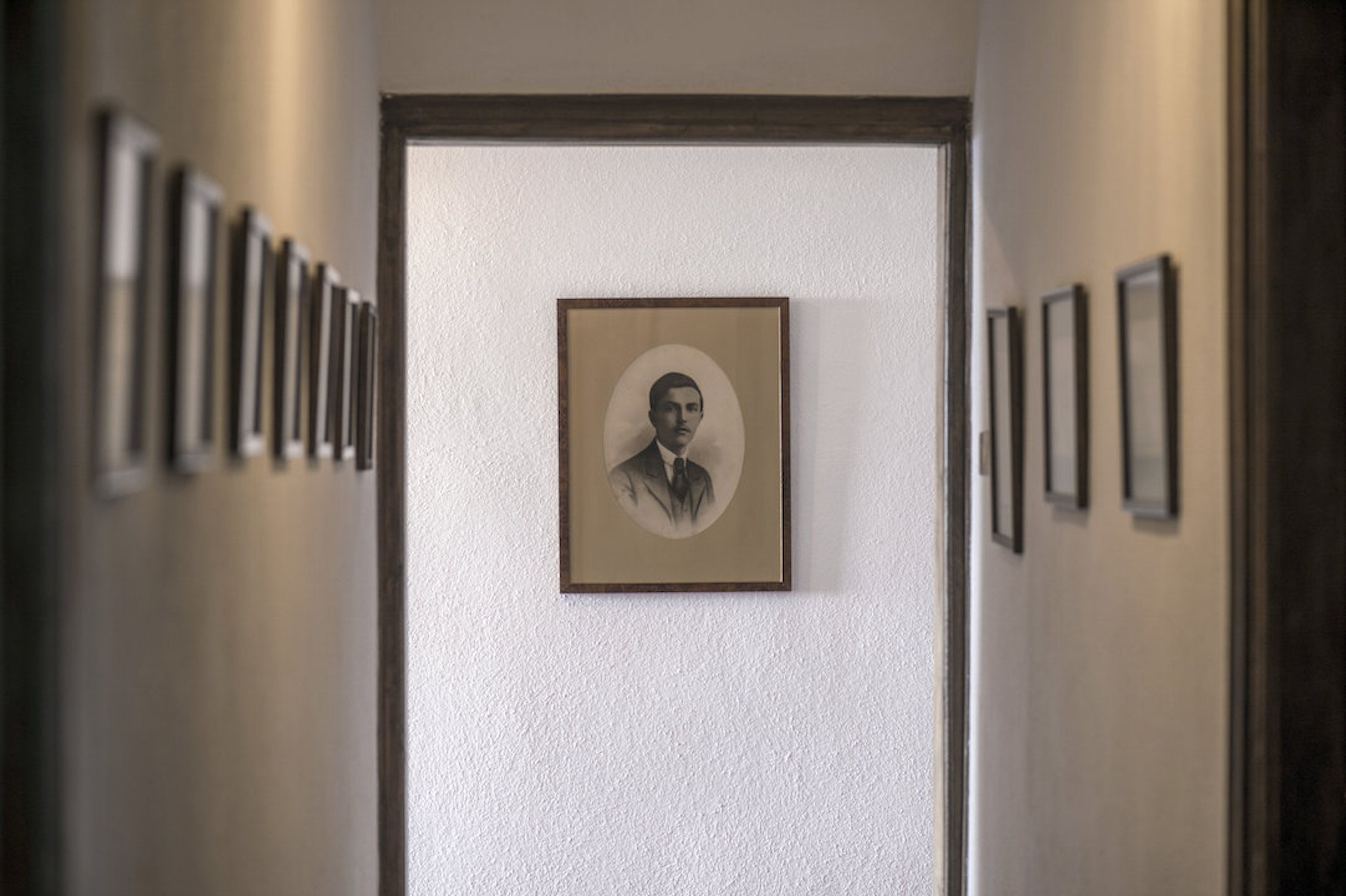 A hallway with framed portraits on the walls.