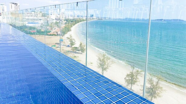 A glass balcony overlooking a beach with a clear view of the sea and distant buildings. - La Vogue Boutique Hotel & Casino (Sihanoukville)