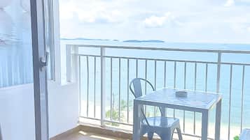 En balkon med et bord og en stol, der udover et vandareal og fjerntliggende land.