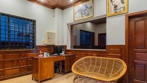 Een kamer met een houten bureau, computer en een rieten stoel.