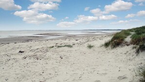 Una playa arenosa con dunas y cielo despejado.