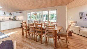 Una cocina moderna con armarios de madera, un comedor con sillas de madera y un ventanal que proporciona luz natural.