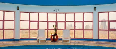 An indoor swimming pool with a view of a city skyline through large windows.
