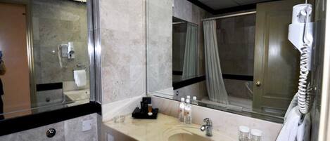 Un baño de hotel con un espejo grande, un lavabo, un teléfono y una zona de ducha.