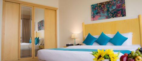 Une chambre d’hôtel avec un lit, une table de chevet, une lampe, un miroir, une armoire et un tableau au mur.