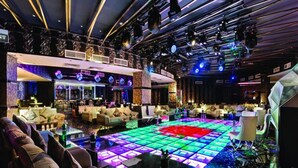 Un área de lounge moderna con una pista de baile central, varias zonas de estar y un bar.