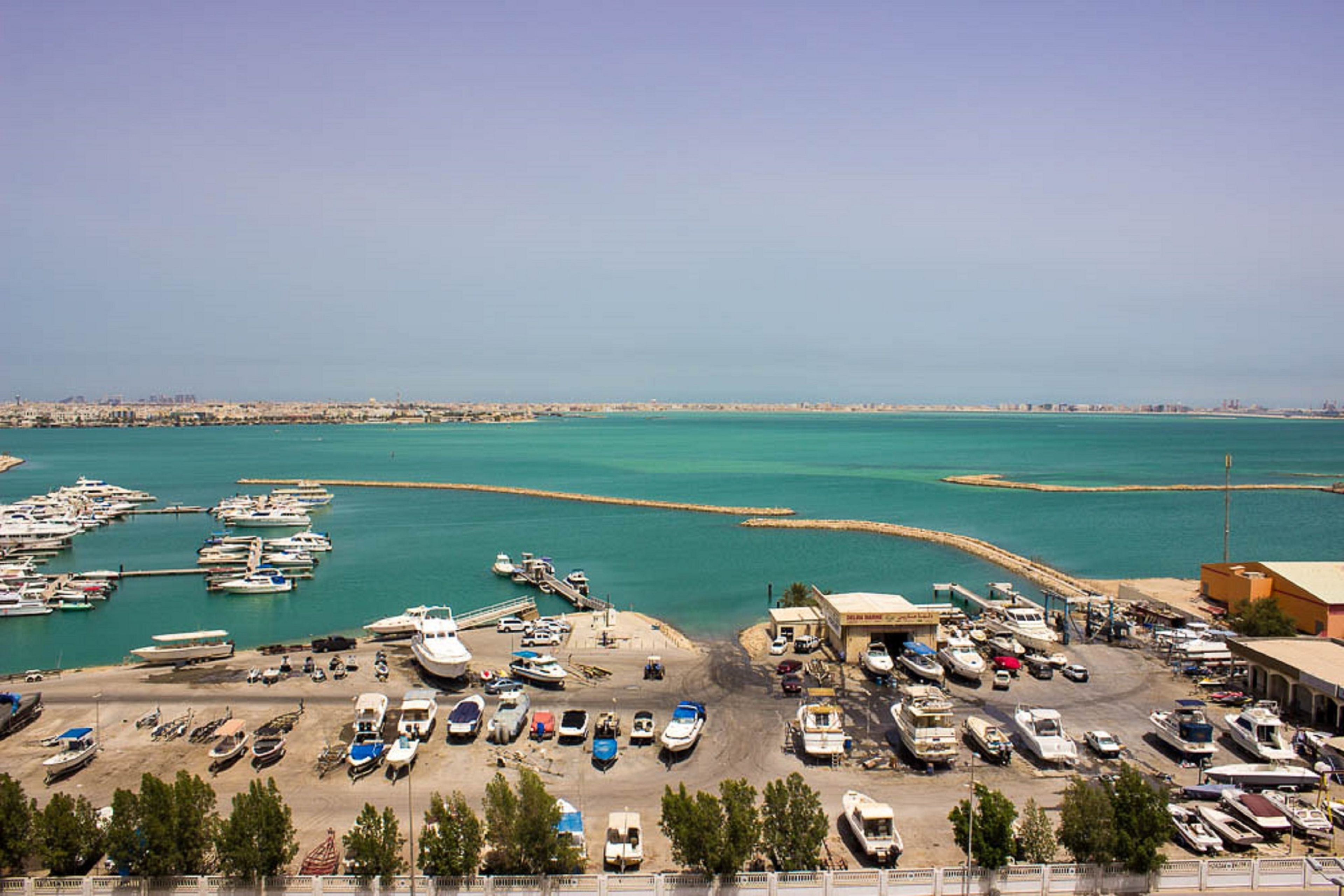 Un puerto deportivo con barcos amarrados y una zona de playa arenosa.