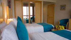 Una habitación de hotel con dos camas, un armario de madera, una silla y una mesa con fruta.