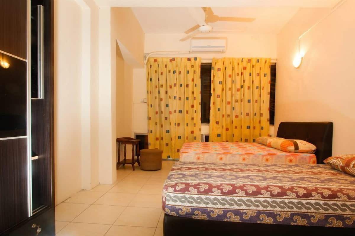 Ein Hotelzimmer mit zwei Betten, einem Deckenventilator, einer Klimaanlage und einem kleinen Tisch mit einem Stuhl.