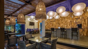 A restaurant with wicker furniture, hanging lights, and a wooden wall design. - KAI Hikkaduwa (Hikkaduwa)