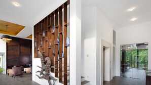 A modern interior with a wooden bookshelf, a unique sculpture, and a staircase leading to a balcony with a view of greenery. - KAI Hikkaduwa (Hikkaduwa)