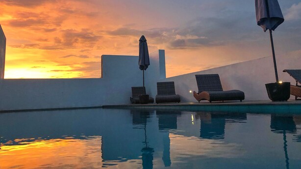 A poolside area with lounge chairs and umbrellas, reflecting a sunset sky. - KAI Hikkaduwa (Hikkaduwa)