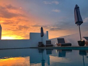 A poolside area with lounge chairs and umbrellas, reflecting a sunset sky. - KAI Hikkaduwa (Hikkaduwa)